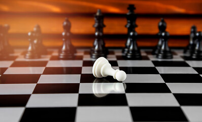 The white pawn in a combat chess game lies alone opposite the opponent's black pieces