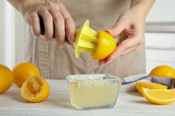Woman squeezing lemon juice with reamer at table, closeup