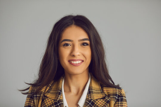 Headshot portrait of nice millennial brunette hispanic woman in shirt, jacket smiling looking at camera isolated on grey studio copy space. Successful latin businesswoman with positive face expression