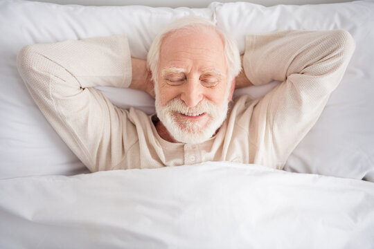 Top above high angle photo of aged man sleep rest relax bedtime comfort cozy happy positive wear pajamas hands behind head home