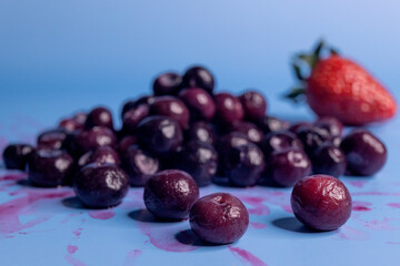mountain of blueberries with a strawberry in the background and an infinite blue background