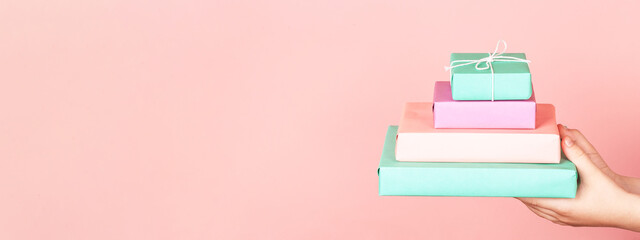 Kid's hands holding four gift boxes in pastel color.