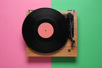 Modern turntable with vinyl record on color background, top view