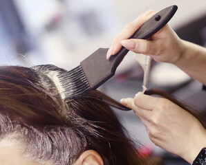 Naklejka premium hairdresser hand with hair dye making haircut and hair coloring on client closeup photo