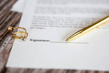 Marriage contract with two golden wedding rings and gold pen, prenuptial agreement, macro close up,...