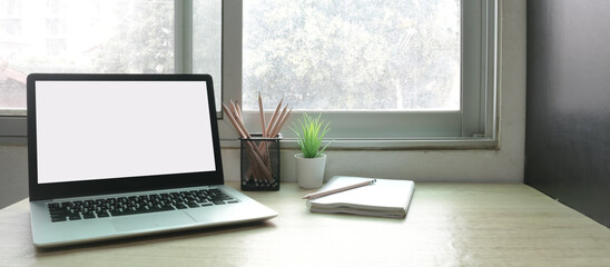 Laptop computer with white blank screen on desk in workspace and copy space concept