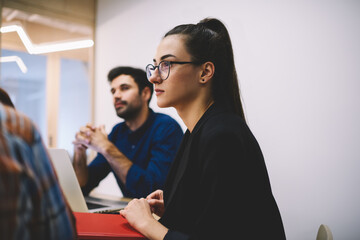 Pensive woman listening colleague while working