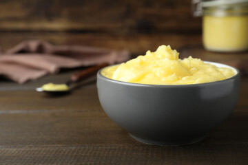 Bowl of Ghee butter on wooden table, closeup. Space for text