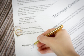 Marriage contract with two golden wedding rings and gold pen, prenuptial agreement, macro close up, sign with signanture,document,agreement concept