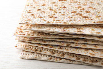 Stack of matzos on white wooden table, closeup