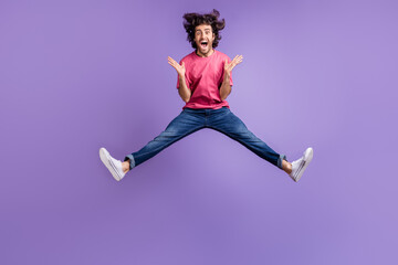 Full size photo of impressed nice brunet guy jump wear pink t-shirt jeans isolated on violet background