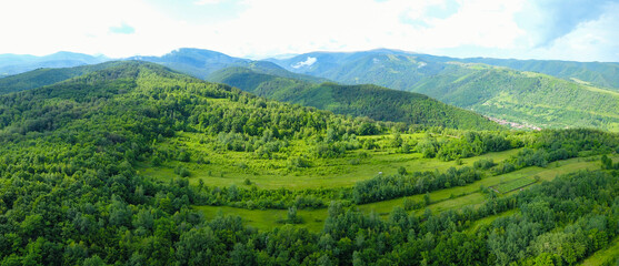 Aerial drone view above the hills at the feet of Parang Mountains. The hills were used for agriculture, but now beech forests have retaken the lands. Carpathia, Romania.
