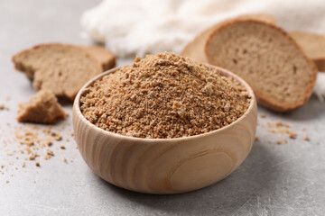Fresh bread crumbs in bowl on grey table, closeup