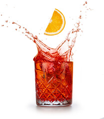 Orange slice falling in a classic Negroni Americano cocktail isolated on white background. Splashing before dinner drink..