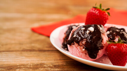 Homemade strawberry ice cream on white plate on a rustic background.