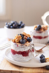 Chia seeds pudding with strawberry jam, granola, blueberry in glass jars 