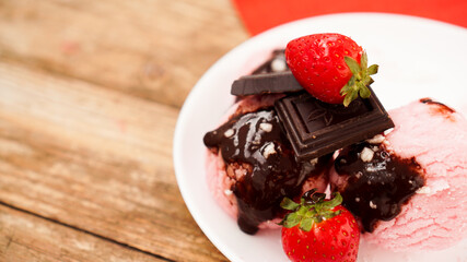 Homemade strawberry ice cream on white plate on a rustic background.