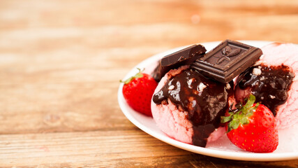 Homemade strawberry ice cream on white plate on a rustic background.