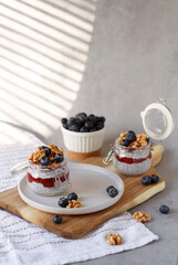 Chia seeds pudding with strawberry jam, granola, blueberry in glass jars 
