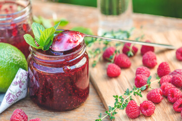 Raspberry jam and fresh raspberry on a rustic wooden table in the garden.