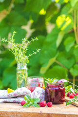 Raspberry jam and fresh raspberry on a rustic wooden table in the garden.