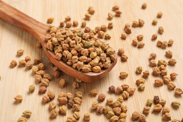 Dried chickpeas in wooden spoon on wooden background.