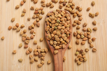 Dried chickpeas in wooden spoon on wooden background.