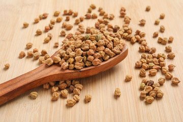 Dried chickpeas in wooden spoon on wooden background.