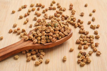 Dried chickpeas in wooden spoon on wooden background.
