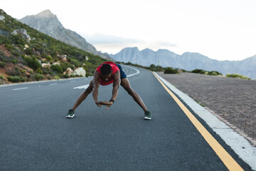 African american man exercising outdoors stretching on a coastal road