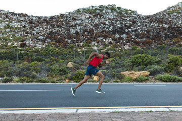 African american man exercising outdoors running on a coastal road