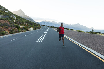 African american man exercising outdoors running on a coastal road