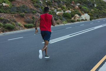 African american man exercising outdoors running on a coastal road