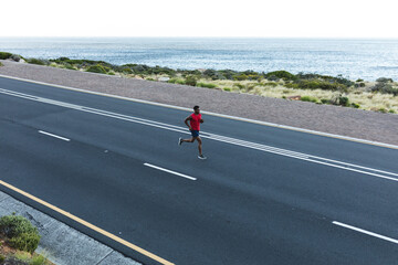 African american man exercising outdoors running on a coastal road
