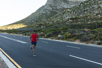 African american man exercising outdoors running on a coastal road
