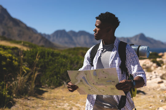 African american man exercising outdoors reading map in countryside on a mountain