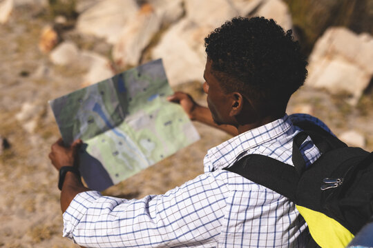 African american man exercising outdoors reading map in countryside on a mountain