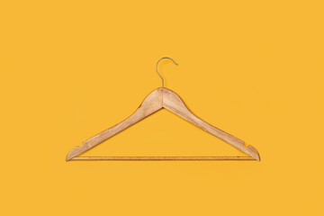 Percha marrón de madera sobre un fondo amarillo liso y aislado. Vista superior. Copy space