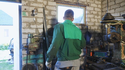 Happy mechanic in protective glasses dancing funny during working in workshop. Young man in uniform enjoying and having fun in garage. Cheerful repairman fooling around at workplace. Dolly shot