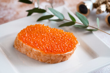 White bread with red caviar and butter on a white plate. Seafood sandwiches in the buffet, selective focus