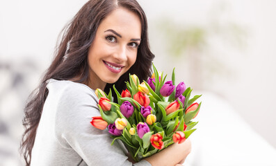 Naklejka premium Happy dark haired woman holding a lovely bouquet full of tulips during national womens day
