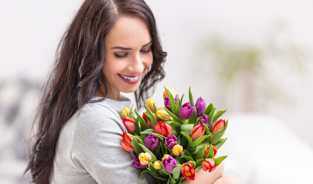 Happy dark haired woman holding a lovely bouquet full of tulips during national womens day
