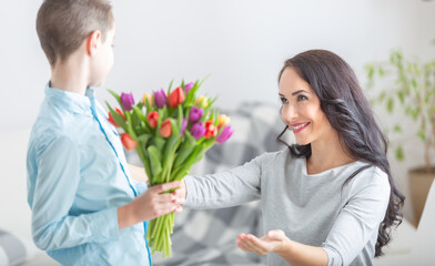 Young mother receiving a bouquet full of tulips from his son during national mothers day