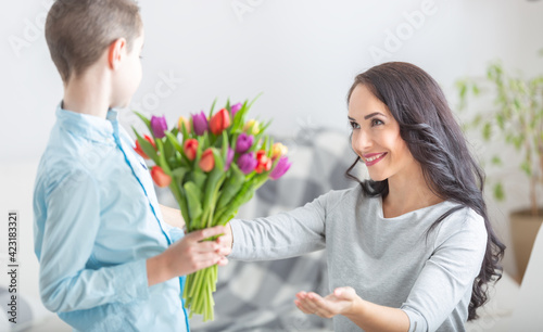 Young mother receiving a bouquet full of tulips from his son during national mothers day