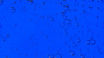 Oil bubbles on the water surface in motion, on a blue background, macro, splash screen, template, copy space