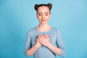 Photo o calm pretty girl hold hands heard chest enjoy closed eyes isolated on pastel blue color background