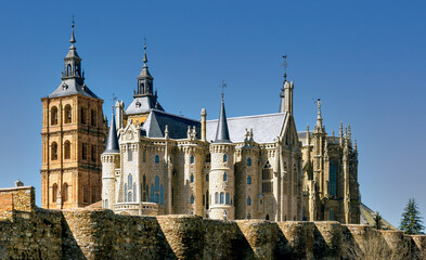 View of historic cathedral and landmark Gaudi building surrounded by ancient Roman  surrounding wall in the city of Astorga, Spain.