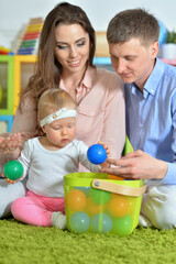 Parents playing with adorable little daughter at playroom