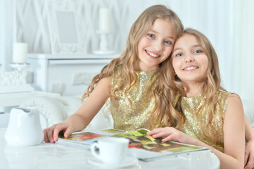 cute twin sisters with modern magazine