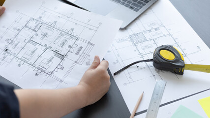 Architectural building design and construction plans with blueprints, Young man was designing a building or architecture with a ruler, pen, pencil, tape measure, architect hat.